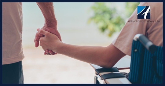 Two people holding hands one in wheelchair